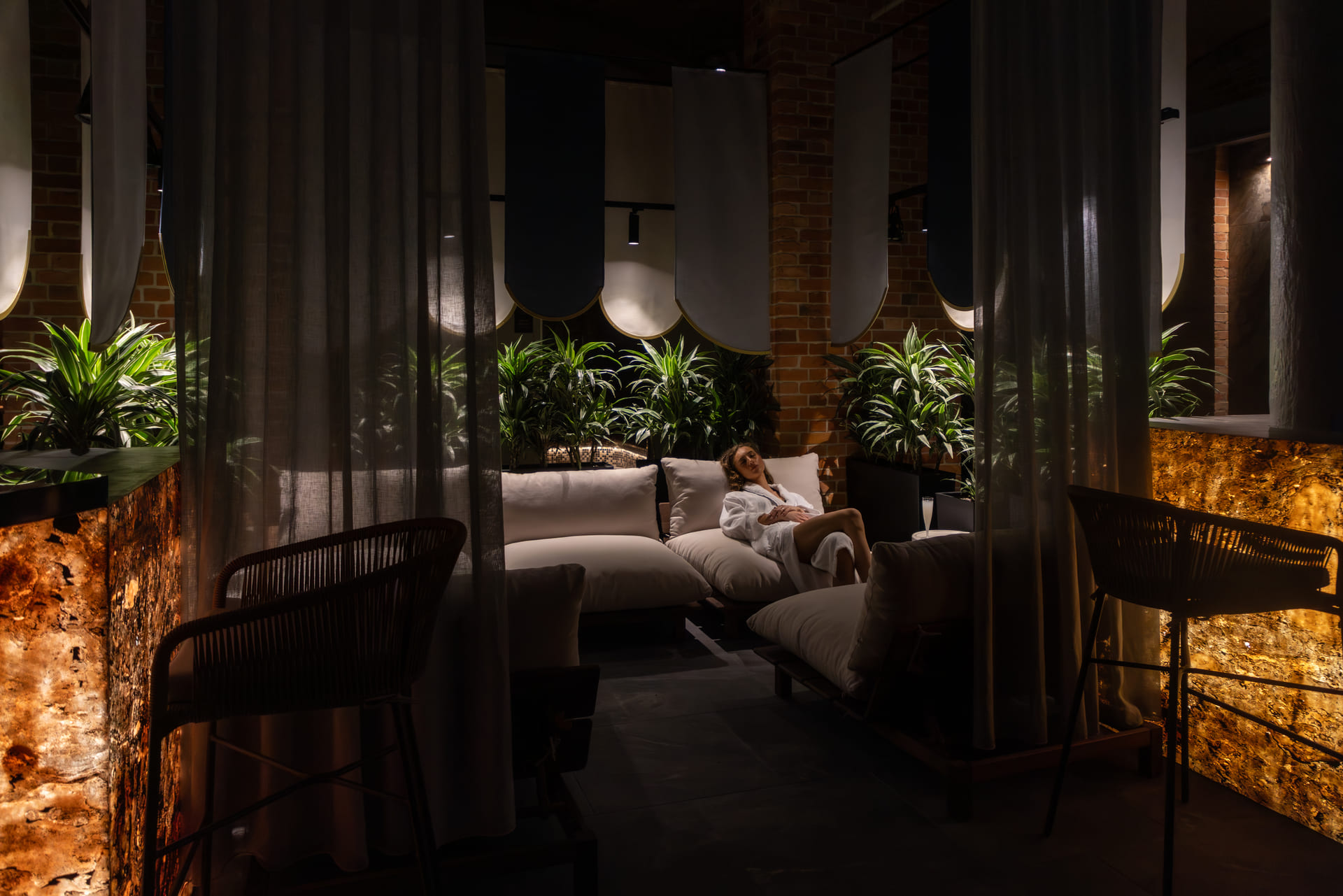 Spokojny salon spa z podświetlanym onyksem, bujną roślinnością i odpoczywającym gościem